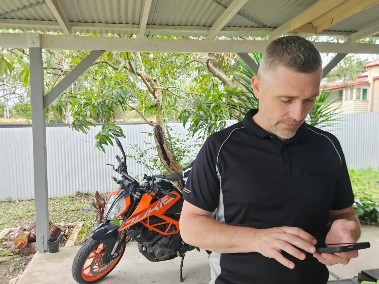 Mechanic using a tablet to record motorbike inspection details beside KTM Duke.